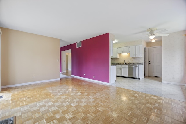 unfurnished living room with ceiling fan, baseboards, and visible vents