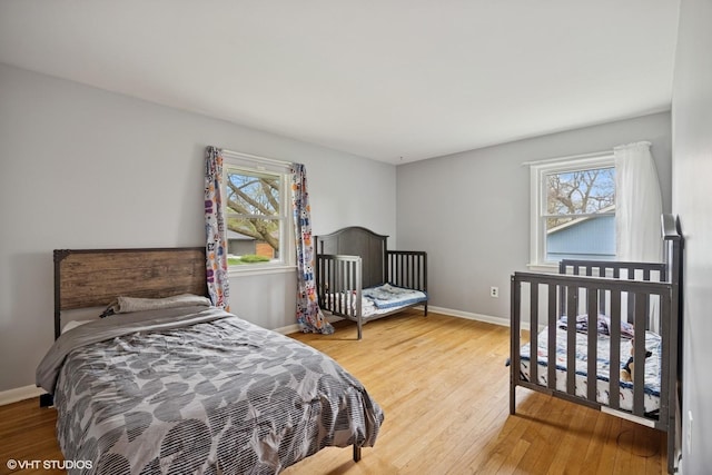 bedroom with baseboards, multiple windows, and wood finished floors