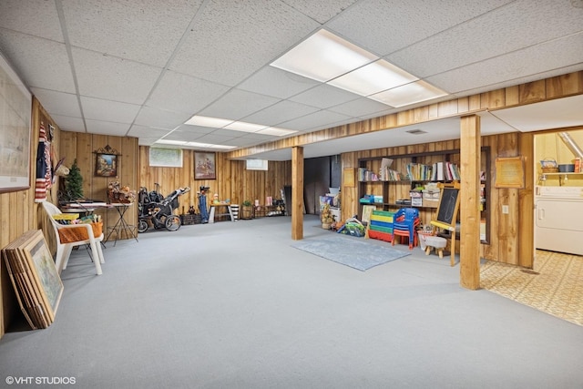 below grade area with washer / clothes dryer, wooden walls, a drop ceiling, and carpet