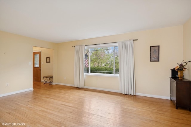 spare room featuring baseboards and light wood-type flooring