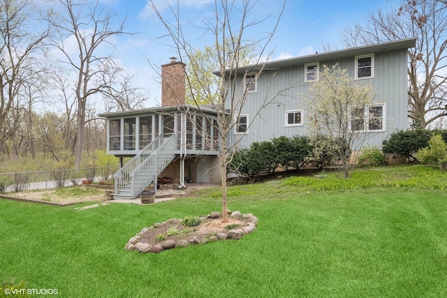 back of property with fence, stairs, a sunroom, a chimney, and a lawn
