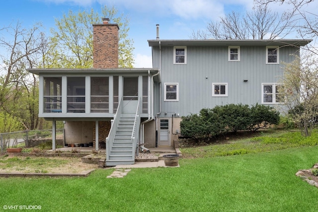 rear view of house featuring a sunroom, stairs, a yard, and a chimney