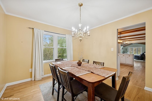 dining space featuring baseboards, ornamental molding, light wood finished floors, and a chandelier