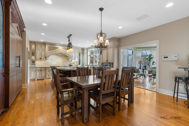 dining area featuring light wood-type flooring, baseboards, an inviting chandelier, and recessed lighting