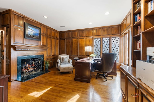 office space with visible vents, a premium fireplace, wood finished floors, and recessed lighting