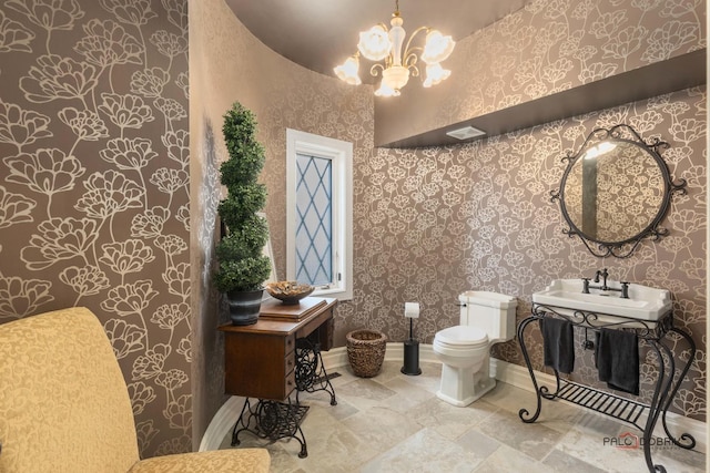 half bathroom with toilet, a sink, wallpapered walls, baseboards, and a notable chandelier