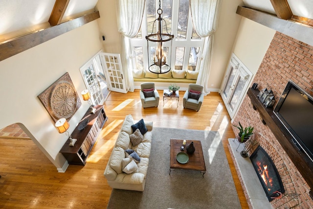 living room with baseboards, wood finished floors, a towering ceiling, and a fireplace