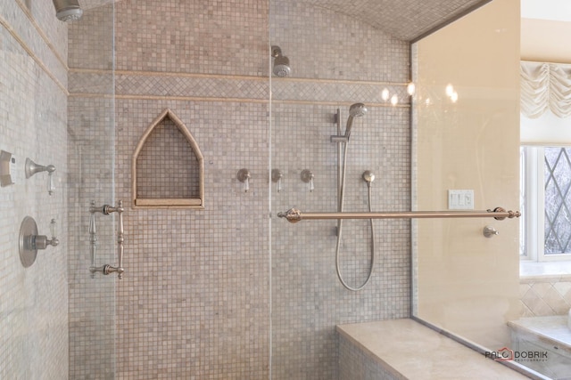bathroom with vaulted ceiling and tiled shower