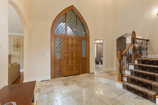 entrance foyer with stone tile floors, a high ceiling, baseboards, and arched walkways