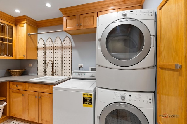 laundry room featuring cabinet space, stacked washer / dryer, recessed lighting, and a sink