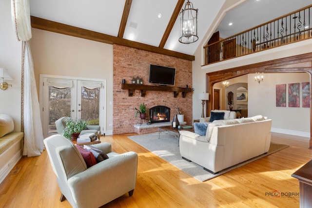 living area featuring light wood finished floors, beam ceiling, arched walkways, high vaulted ceiling, and a fireplace