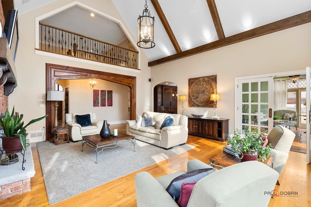living area featuring high vaulted ceiling, arched walkways, and wood finished floors