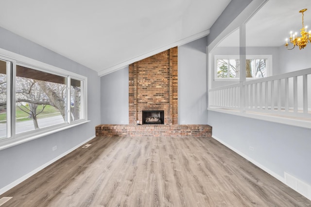 unfurnished living room featuring visible vents, a brick fireplace, vaulted ceiling, wood finished floors, and a notable chandelier