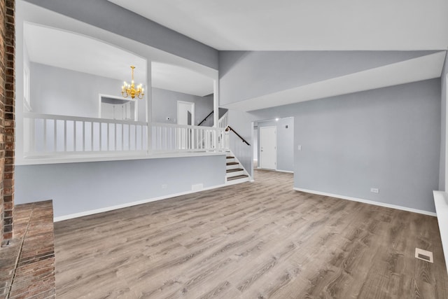 unfurnished living room featuring visible vents, wood finished floors, baseboards, a chandelier, and stairs