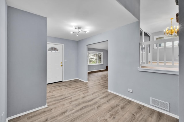 entryway featuring an inviting chandelier, baseboards, wood finished floors, and visible vents