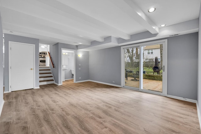 unfurnished living room with beam ceiling, recessed lighting, baseboards, wood finished floors, and stairway
