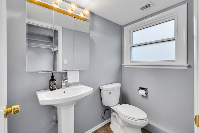 bathroom featuring toilet, baseboards, visible vents, and wood finished floors
