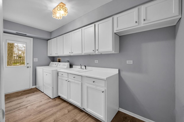 clothes washing area with cabinet space, light wood finished floors, baseboards, visible vents, and washing machine and dryer
