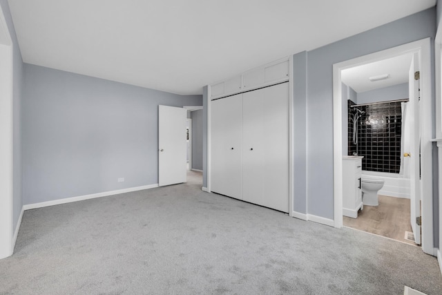 unfurnished bedroom featuring carpet flooring, baseboards, ensuite bathroom, and a closet
