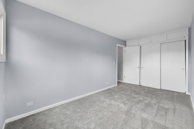 unfurnished bedroom with baseboards, carpet, and a closet
