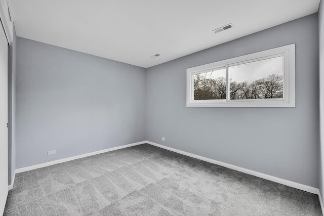 carpeted empty room featuring baseboards and visible vents