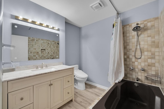 bathroom with visible vents, wood finished floors, vanity, toilet, and shower / bath combo with shower curtain