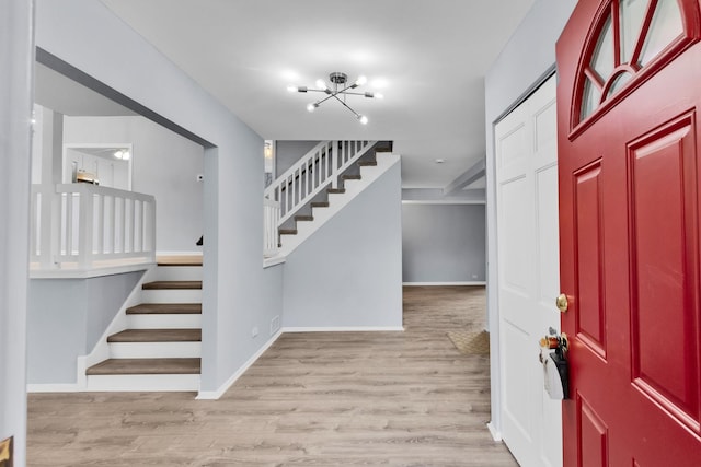 entrance foyer featuring an inviting chandelier, baseboards, stairs, and wood finished floors