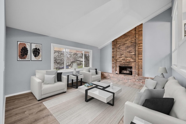 living room featuring vaulted ceiling, wood finished floors, and a brick fireplace
