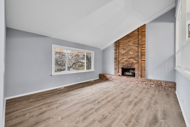 unfurnished living room with a brick fireplace, visible vents, wood finished floors, and lofted ceiling