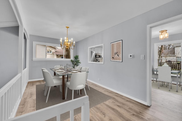 dining space with an inviting chandelier, baseboards, and wood finished floors
