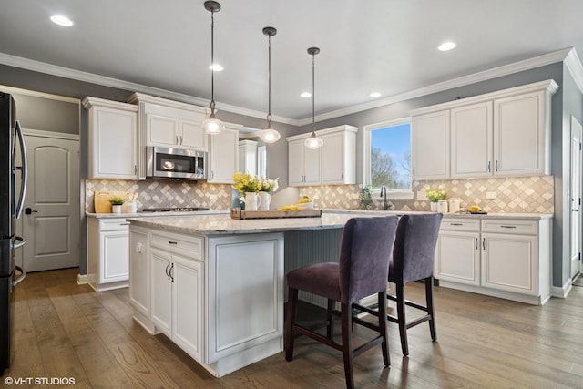 32 E Peter Ln, Hawthorn Woods, IL 60047 - kitchen featuring stainless steel microwave, a center island, white cabinetry, tasteful backsplash, and crown molding