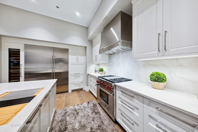 435 N Michigan Ave Unit 401, Chicago, IL 60611 - kitchen featuring light countertops, wall chimney range hood, light wood finished floors, and premium appliances