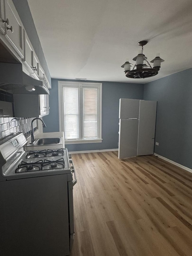 554 Spring St, Aurora, IL 60505 - kitchen with a sink, light wood-type flooring, freestanding refrigerator, a chandelier, and gas stove
