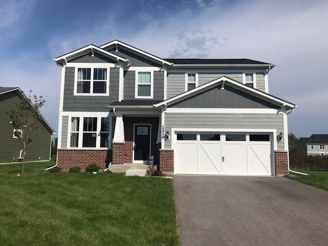 craftsman inspired home with brick siding, a garage, driveway, and a front yard