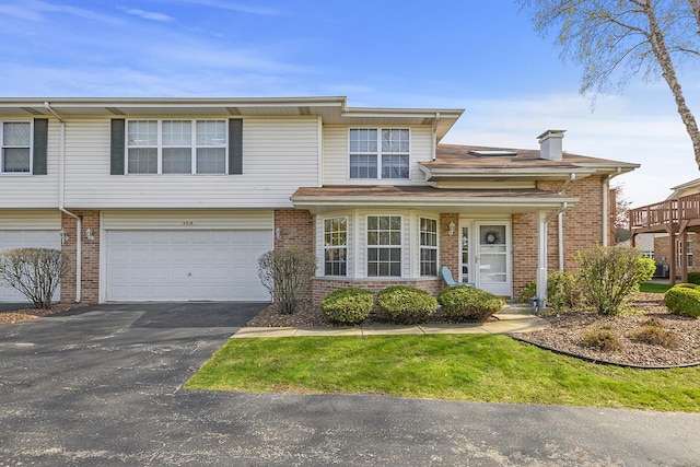 view of front of house with brick siding, driveway, a garage, and a chimney
