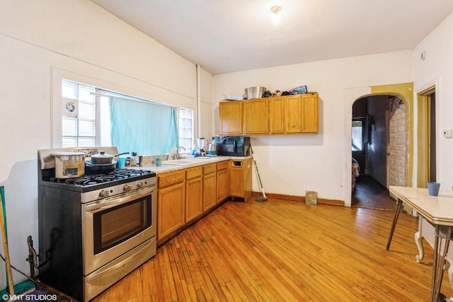 1733 N Keating Ave, Chicago, IL 60639 - kitchen featuring stainless steel range with gas cooktop, a sink, light wood-style floors, light countertops, and brown cabinetry