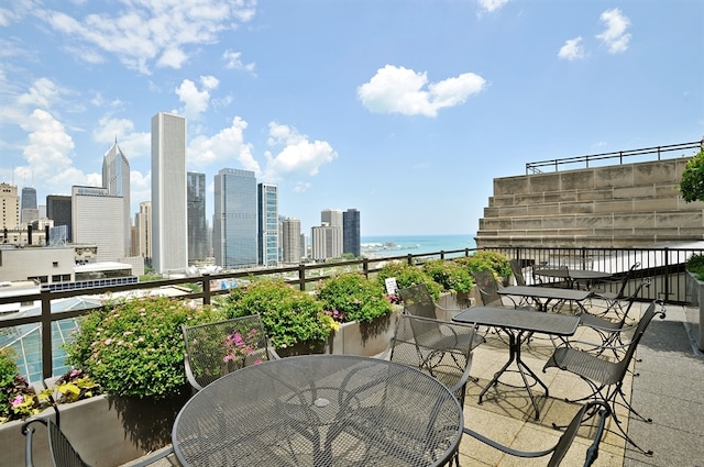 balcony featuring outdoor dining space, a water view, and a skyline view