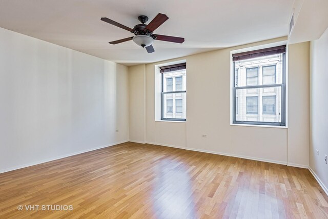unfurnished room with light wood-type flooring, baseboards, and a ceiling fan