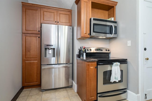 316 E Pierce St, Pontiac, IL 61764 - kitchen featuring appliances with stainless steel finishes, baseboards, brown cabinetry, and dark countertops