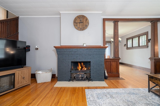 316 E Pierce St, Pontiac, IL 61764 - living room with a brick fireplace, light wood-type flooring, ornate columns, crown molding, and baseboards