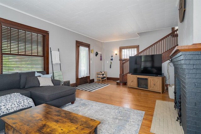 316 E Pierce St, Pontiac, IL 61764 - living area featuring stairway, light wood finished floors, crown molding, a brick fireplace, and baseboards