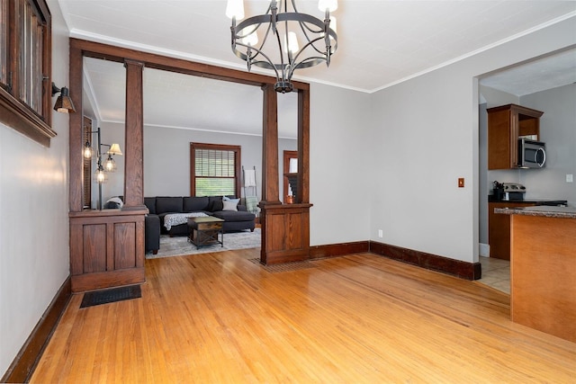 316 E Pierce St, Pontiac, IL 61764 - living room featuring a chandelier, light wood-type flooring, crown molding, baseboards, and ornate columns