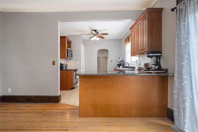316 E Pierce St, Pontiac, IL 61764 - kitchen featuring appliances with stainless steel finishes, dark countertops, brown cabinetry, arched walkways, and a ceiling fan