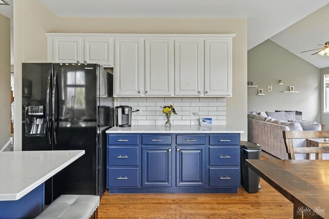 kitchen with white cabinets, ceiling fan, black fridge, and blue cabinets