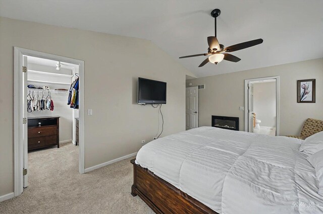 bedroom featuring a walk in closet, visible vents, vaulted ceiling, a closet, and light carpet