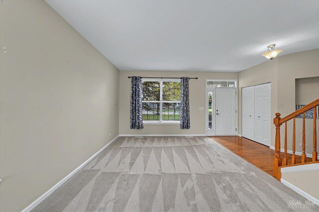 carpeted foyer entrance featuring stairway and baseboards