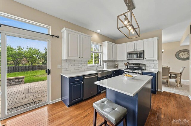 kitchen with decorative backsplash, light countertops, white cabinetry, a sink, and appliances with stainless steel finishes