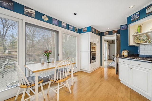 dining room with recessed lighting, crown molding, and light wood-style flooring
