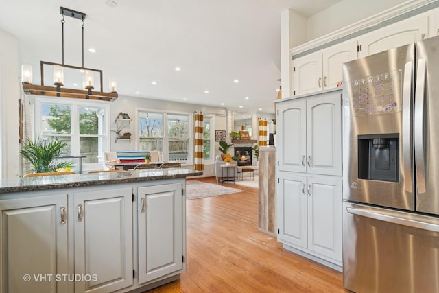 23114 W N Lakewood Ln, Lake Zurich, IL 60047 - kitchen with stainless steel refrigerator with ice dispenser, light wood finished floors, recessed lighting, white cabinets, and a large fireplace