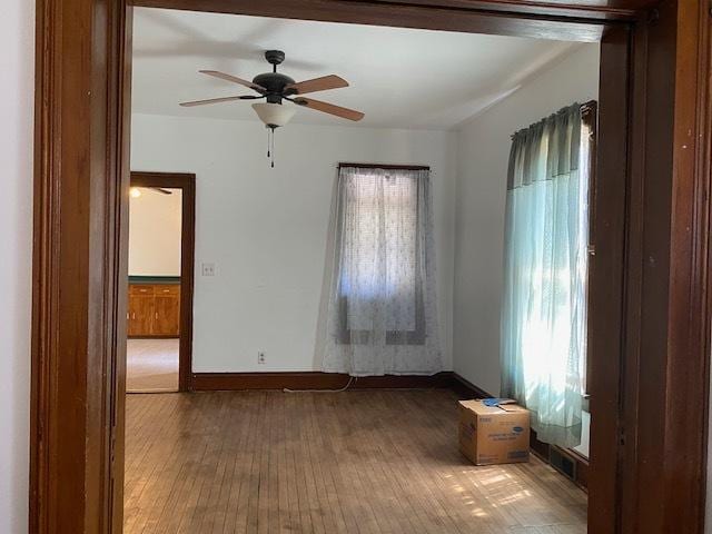 empty room featuring hardwood / wood-style flooring, baseboards, and a ceiling fan